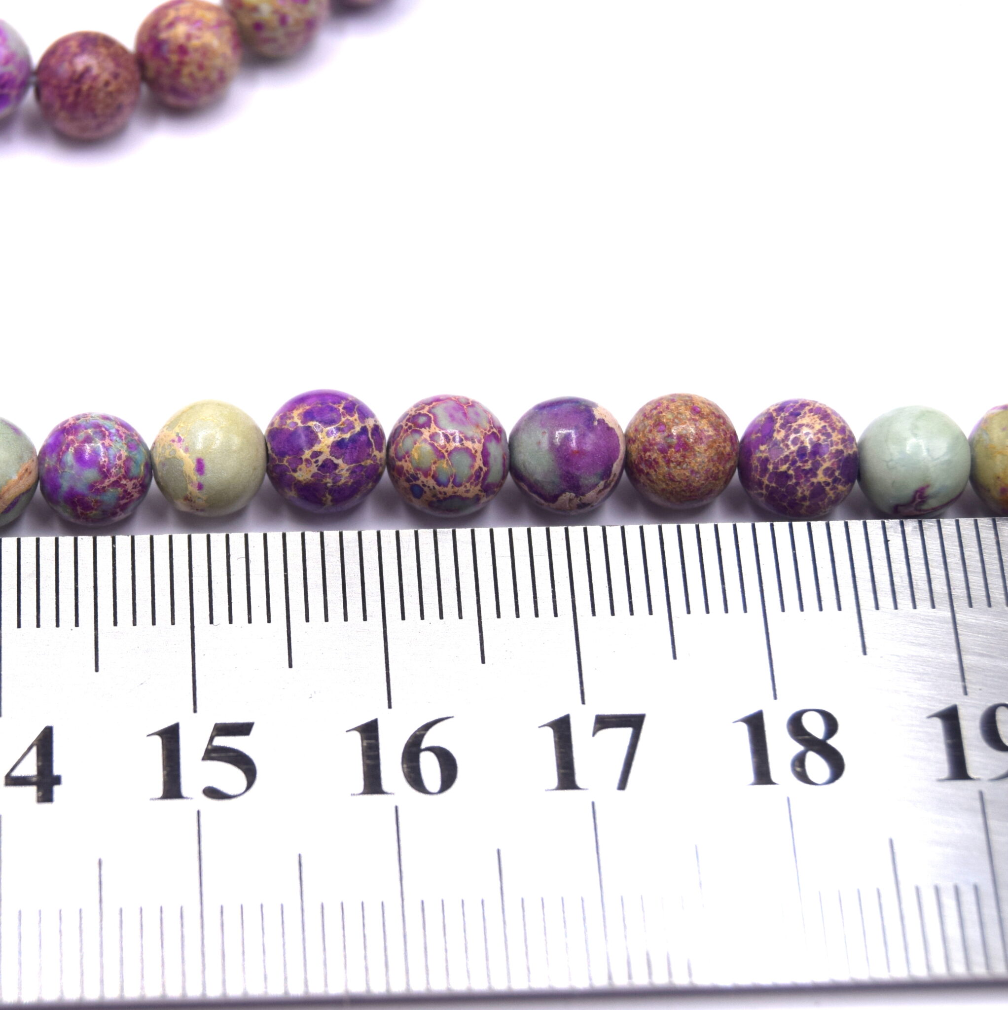 perles-jaspe-imperial-ronde-naturel-teinte-bleu-violet-6mm devant une règle